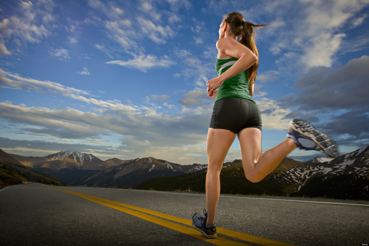 A female road runner runs down a road at dusk at Independence Pass.