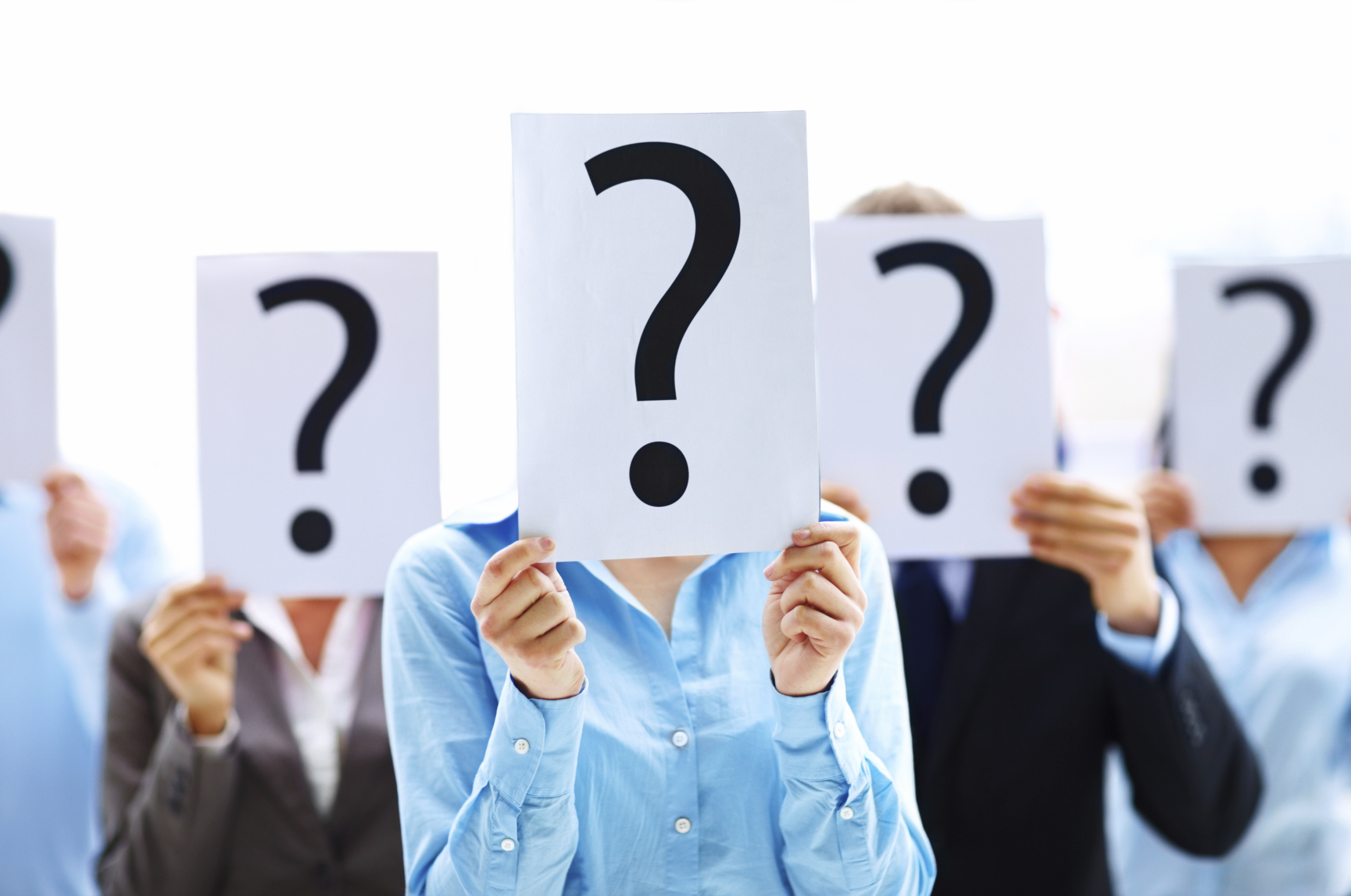 Colleagues holding question mark signs in front of their faces